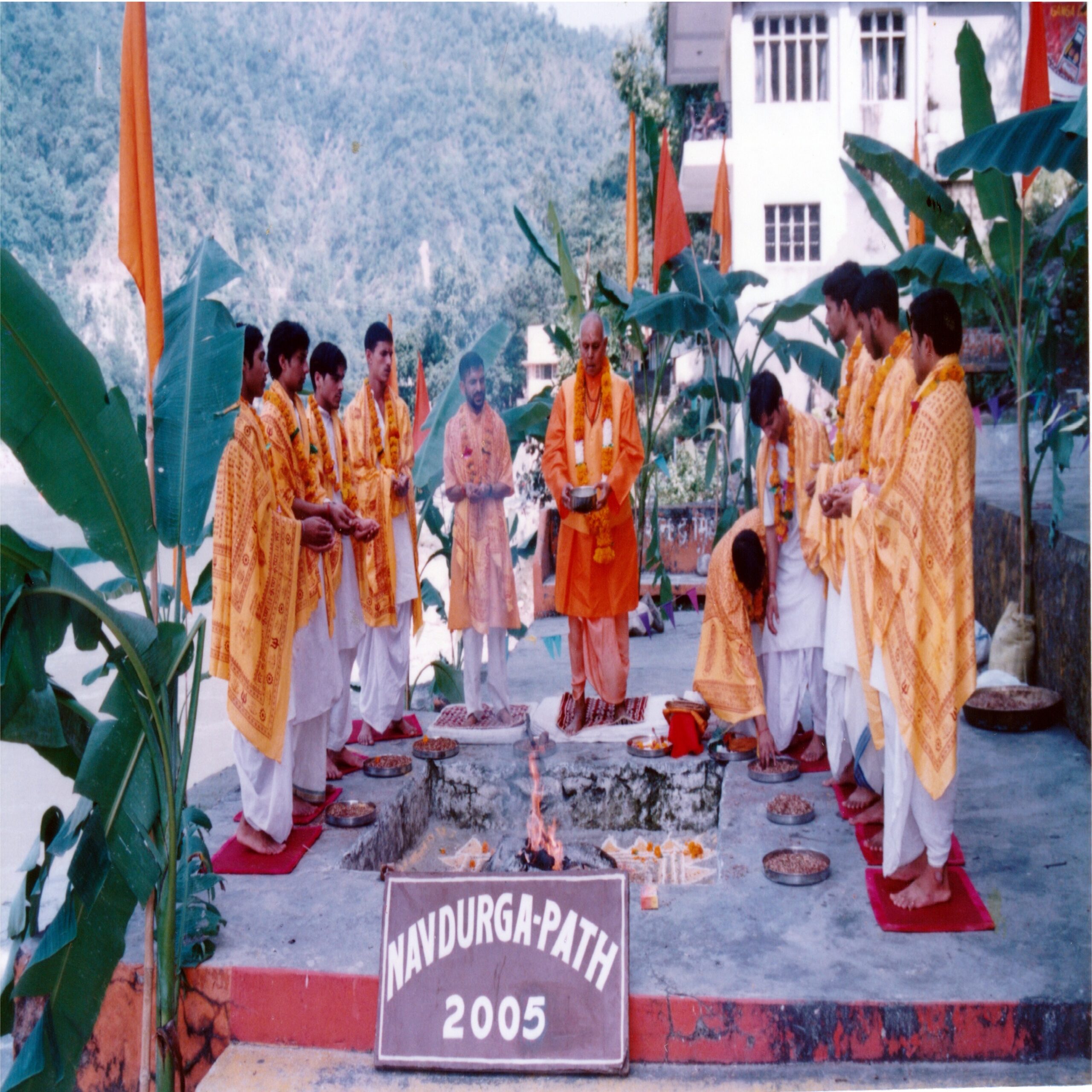 Photo of Yogi Gupta with nine Brahmin priests in a past Navaratra yagna and offering of havis (havan samagri) in the sacred fire while chanting mantras addressing Durga Ma.